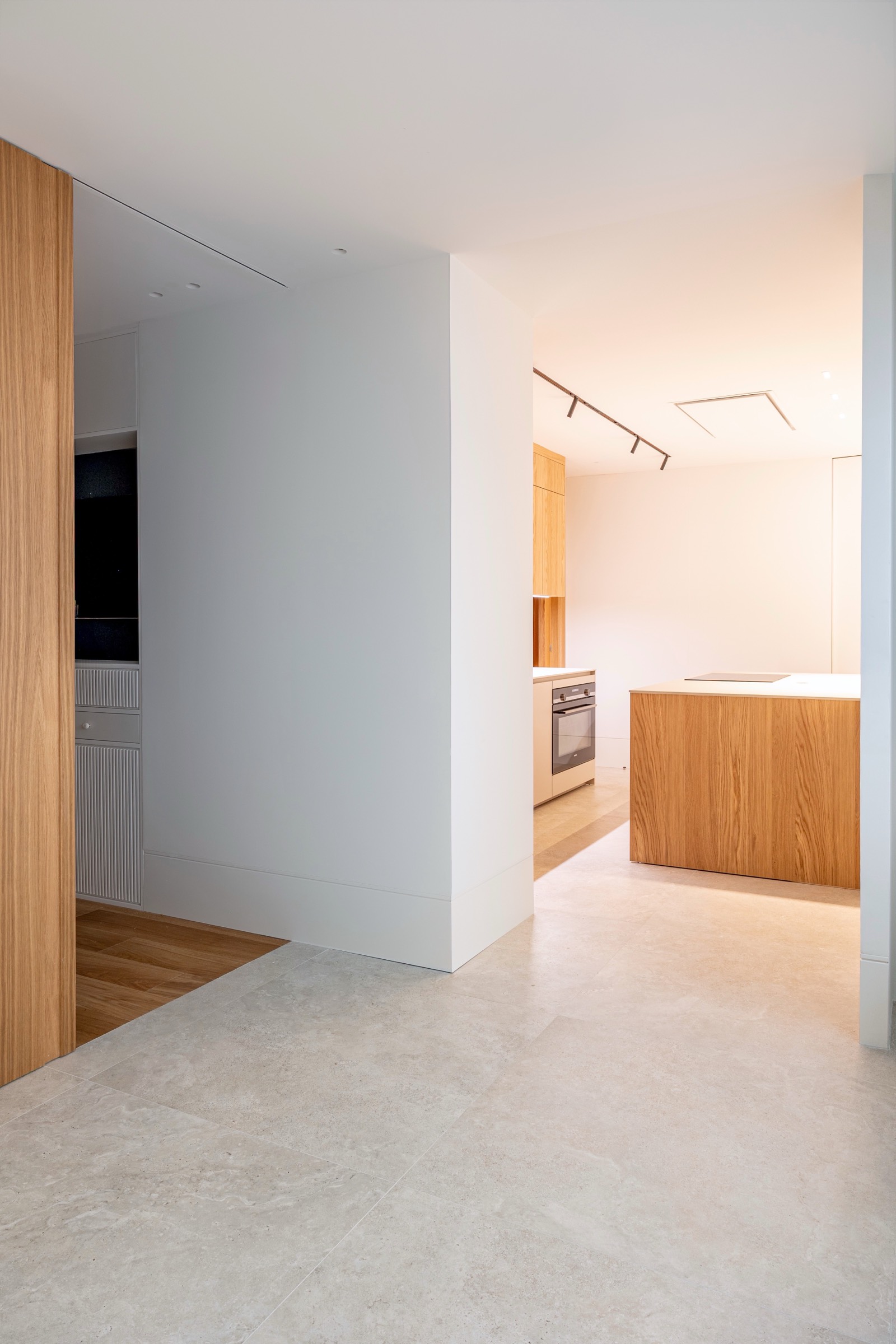 Interior de cocina moderna con paredes blancas, elementos de madera y electrodomésticos empotrados, diseño minimalista y limpio