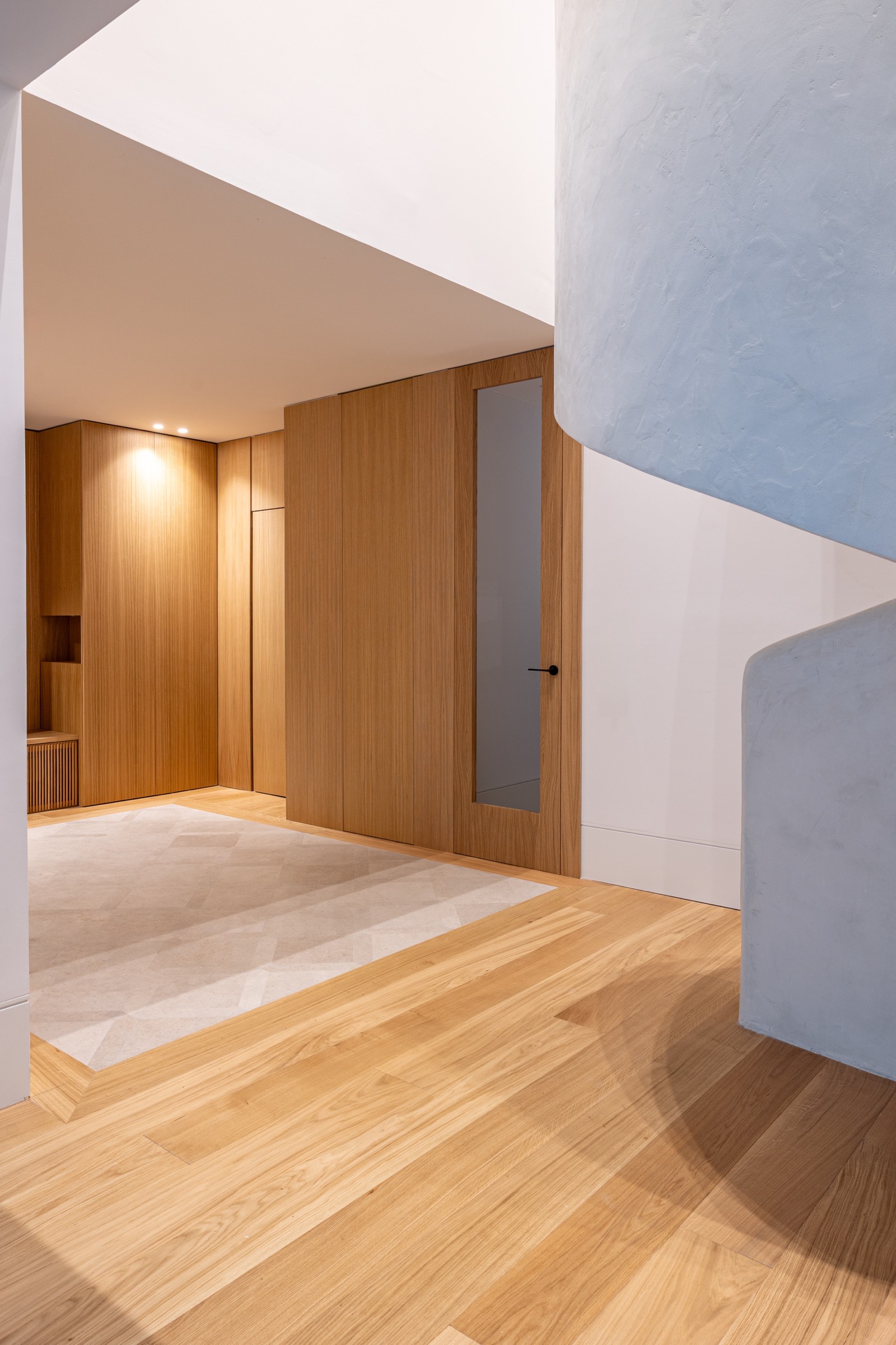 Espacio interior moderno con paredes de madera, suelo de madera clara y paredes blancas y grises con iluminación suave