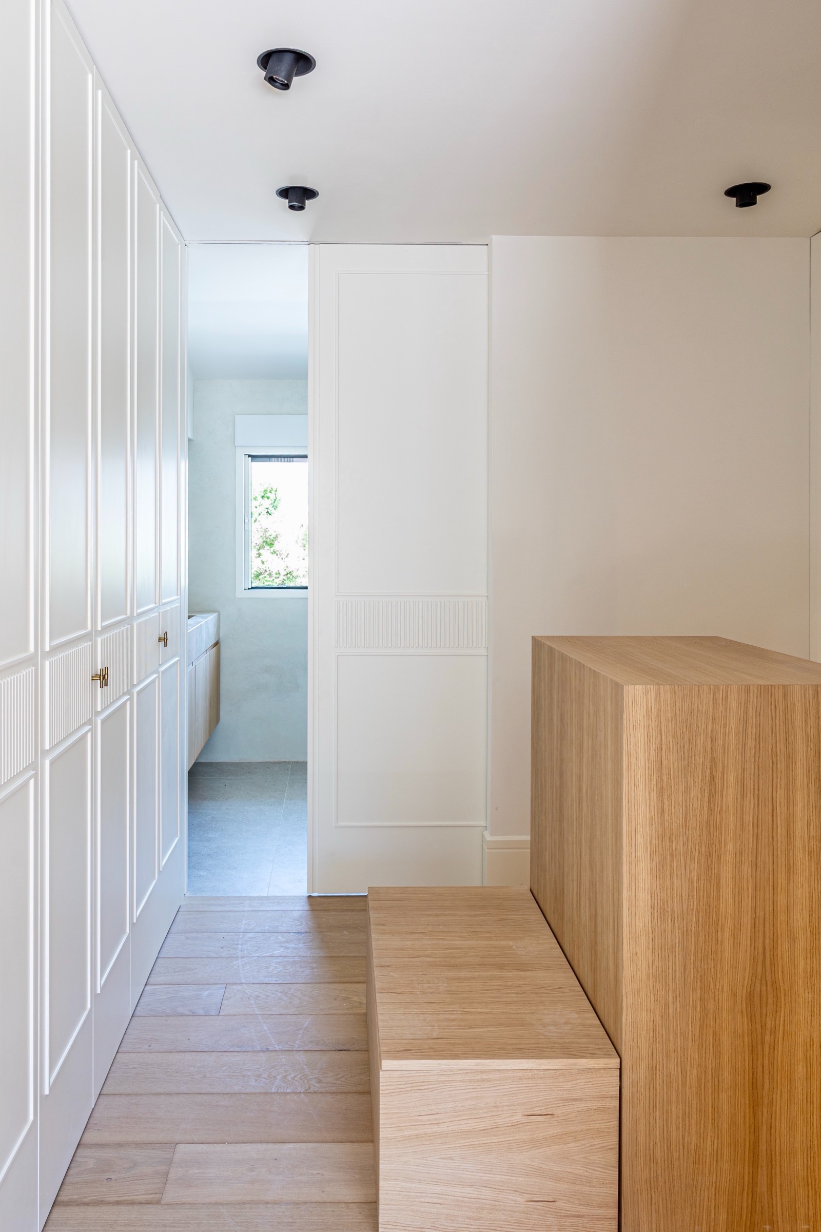 Espacio interior moderno con paredes blancas, armarios empotrados, piso de madera y elementos arquitectónicos minimalistas