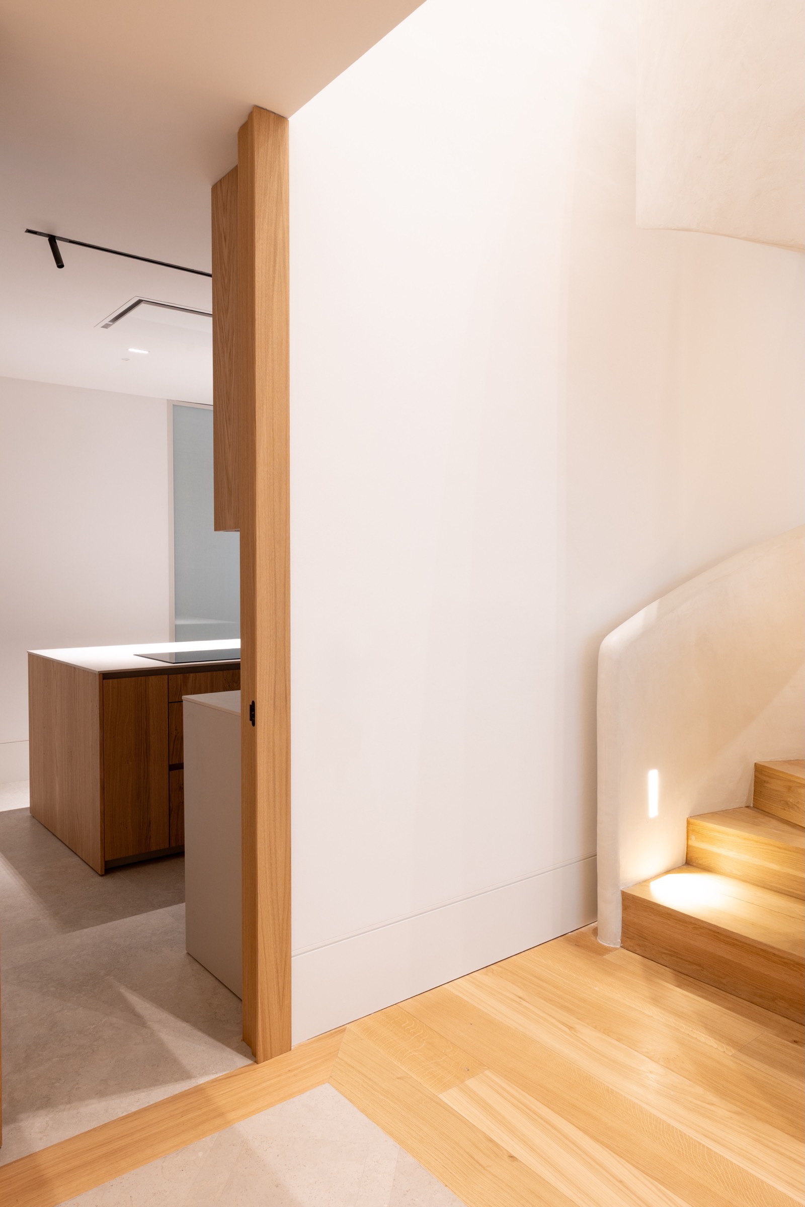 Espacio interior moderno con escaleras de madera, paredes blancas, iluminación suave y elementos de diseño minimalista