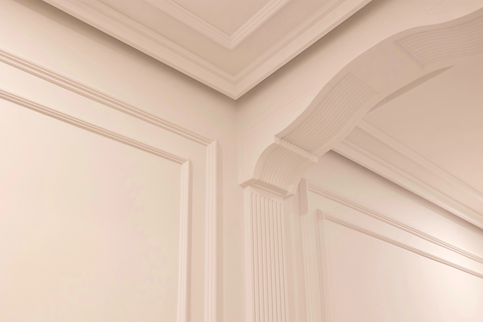 Detalle de molduras decorativas blancas en el interior de una habitación, mostrando cornisas, paneles y columnas con diseños clásicos y elegantes