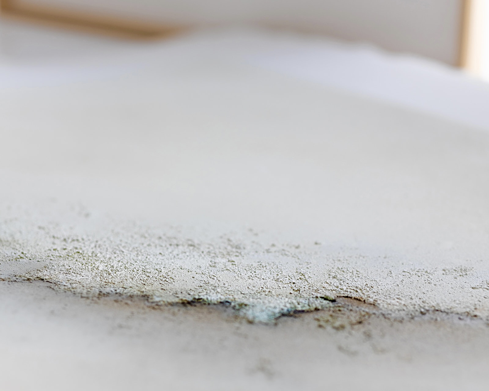 Primer plano de una superficie lisa con una acumulación de polvo o partículas finas en el borde, creando una textura granular contra el fondo liso.