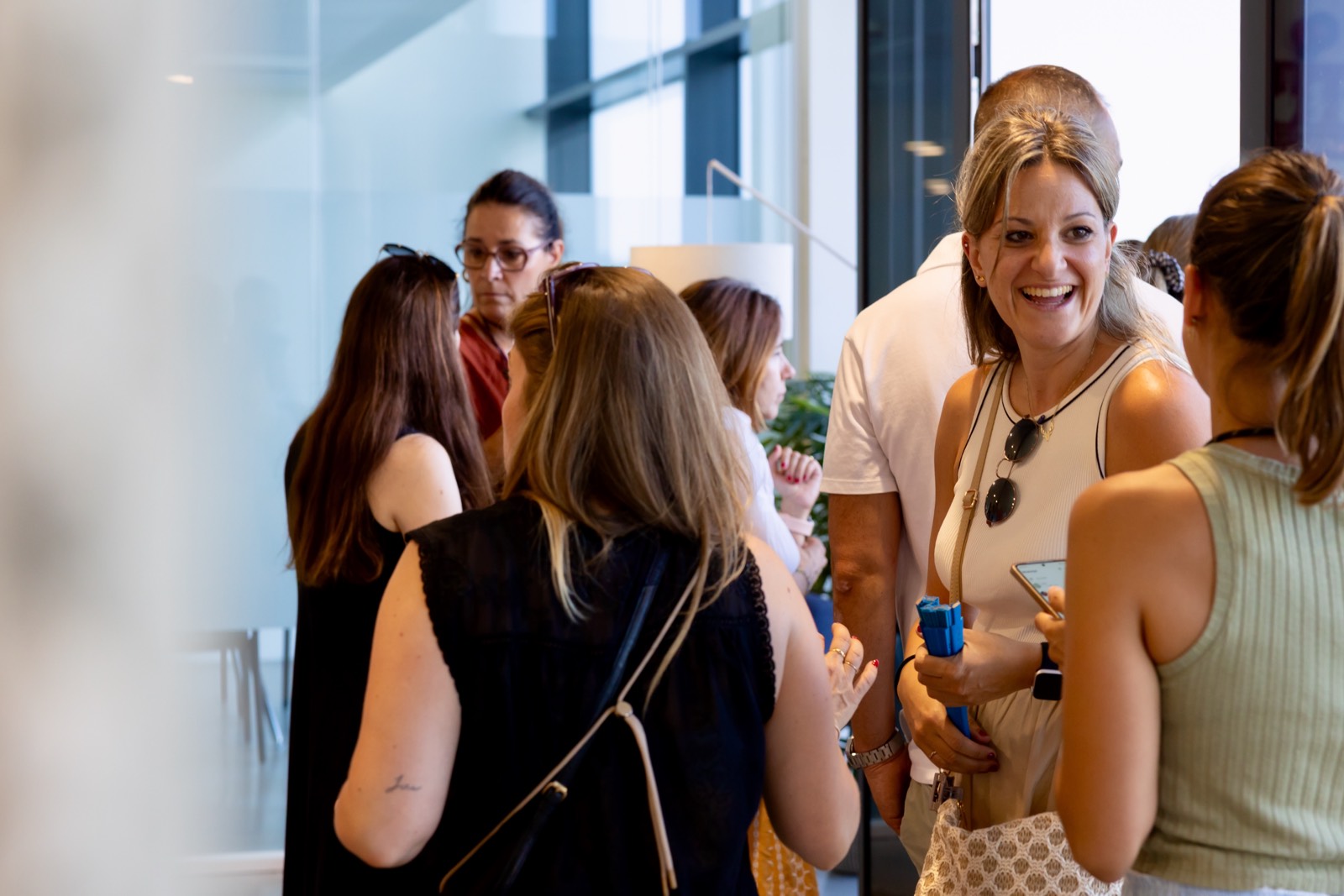 Grupo de profesionales conversando y sonriendo en un entorno de oficina moderno con paredes de vidrio