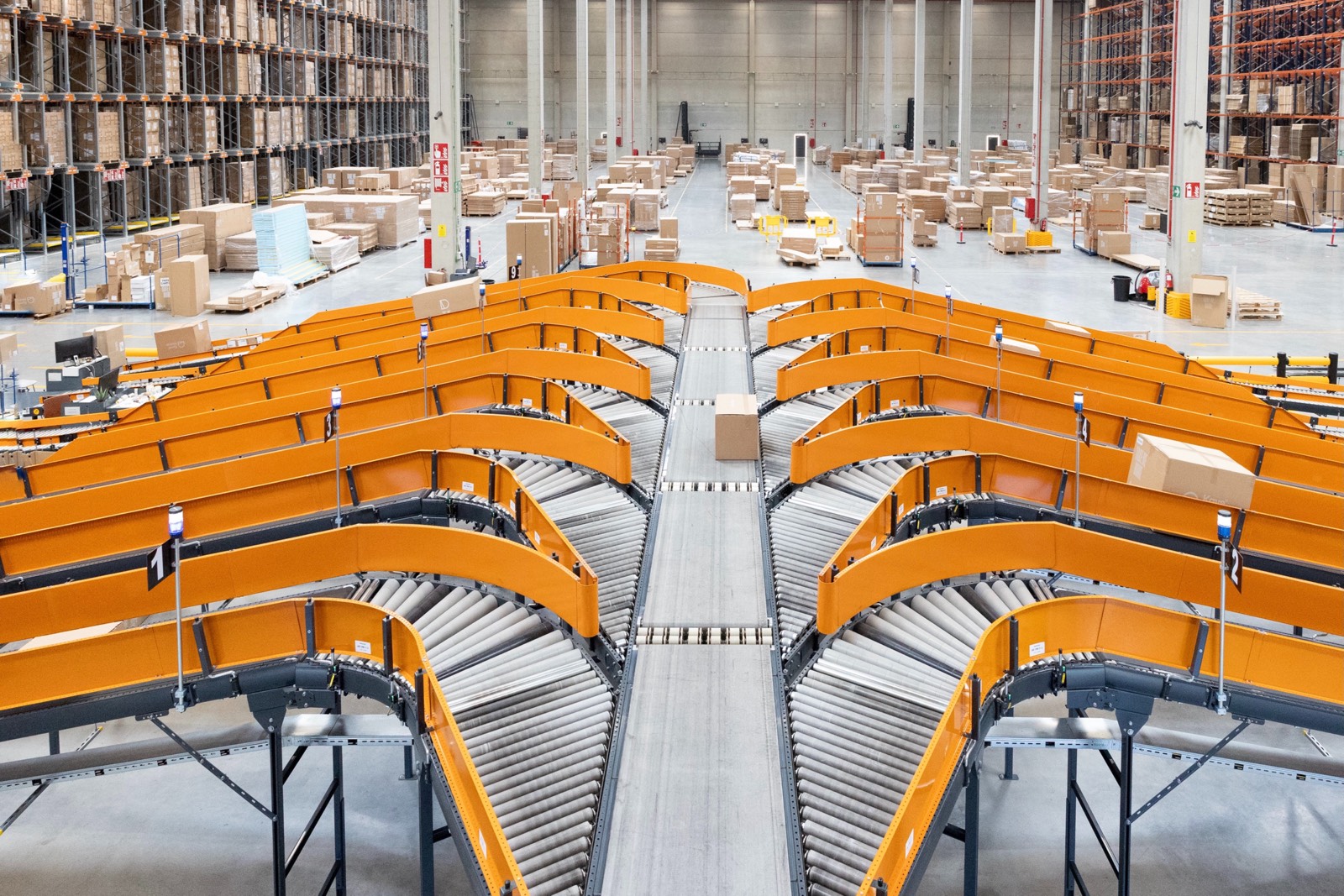 Vista panorámica de un almacén moderno con sistemas de transportadores naranjas y grises para manejo de paquetes y cajas