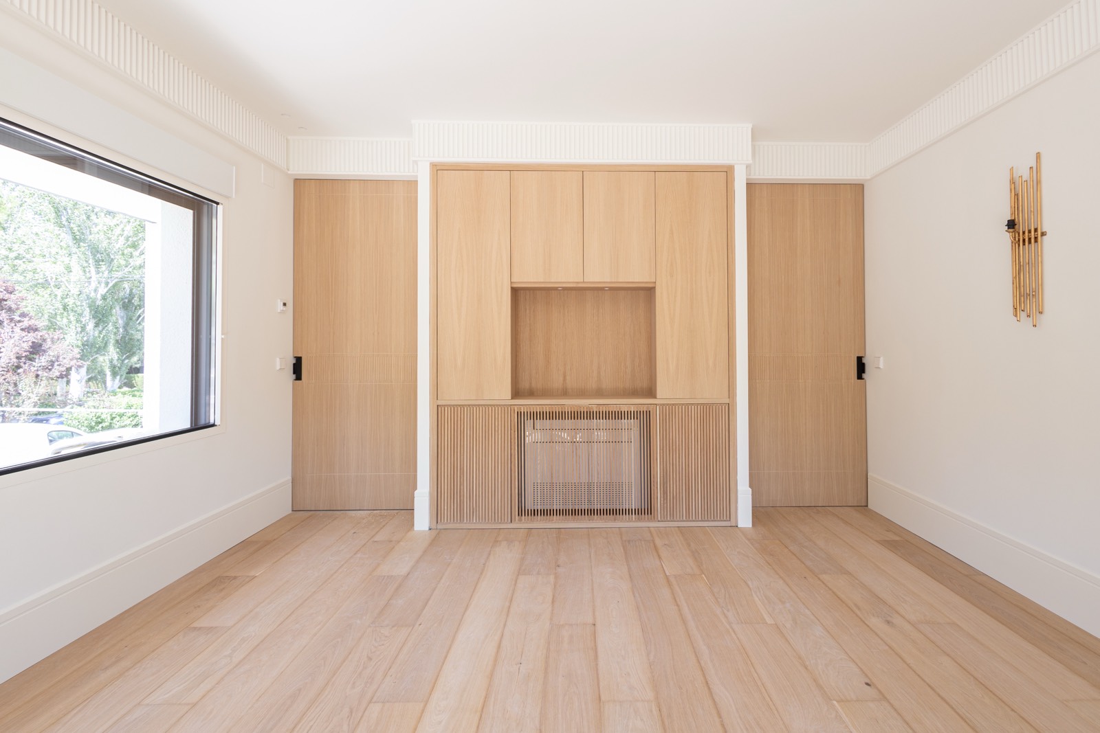 Interior de habitación vacía con paredes, piso y muebles de madera clara, ventana grande y decoración minimalista