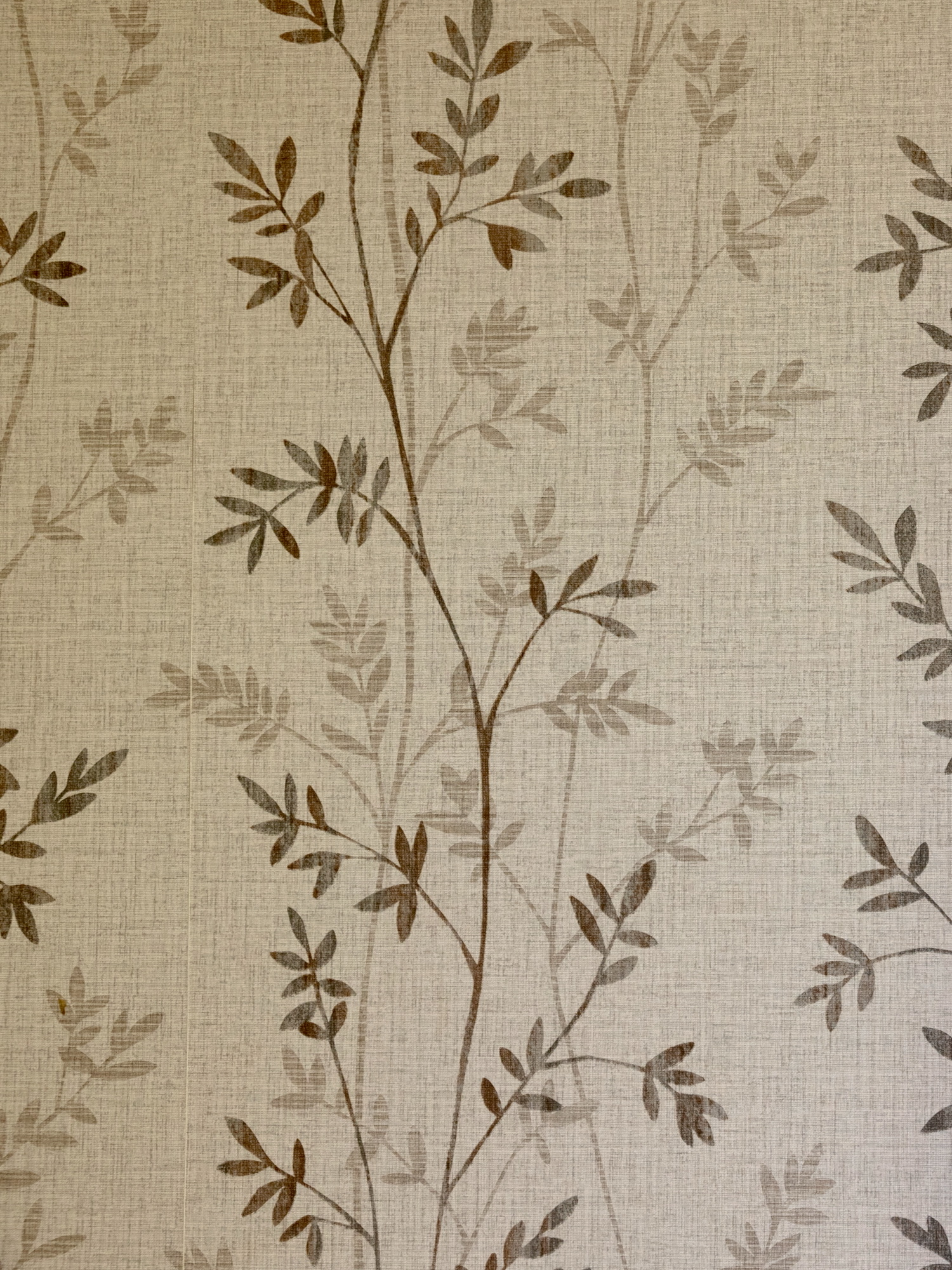 Patrón decorativo de hojas delicadas en tonos marrones sobre un fondo beige texturizado tipo lino. Las ramas y hojas crean un diseño elegante y natural que se repite verticalmente