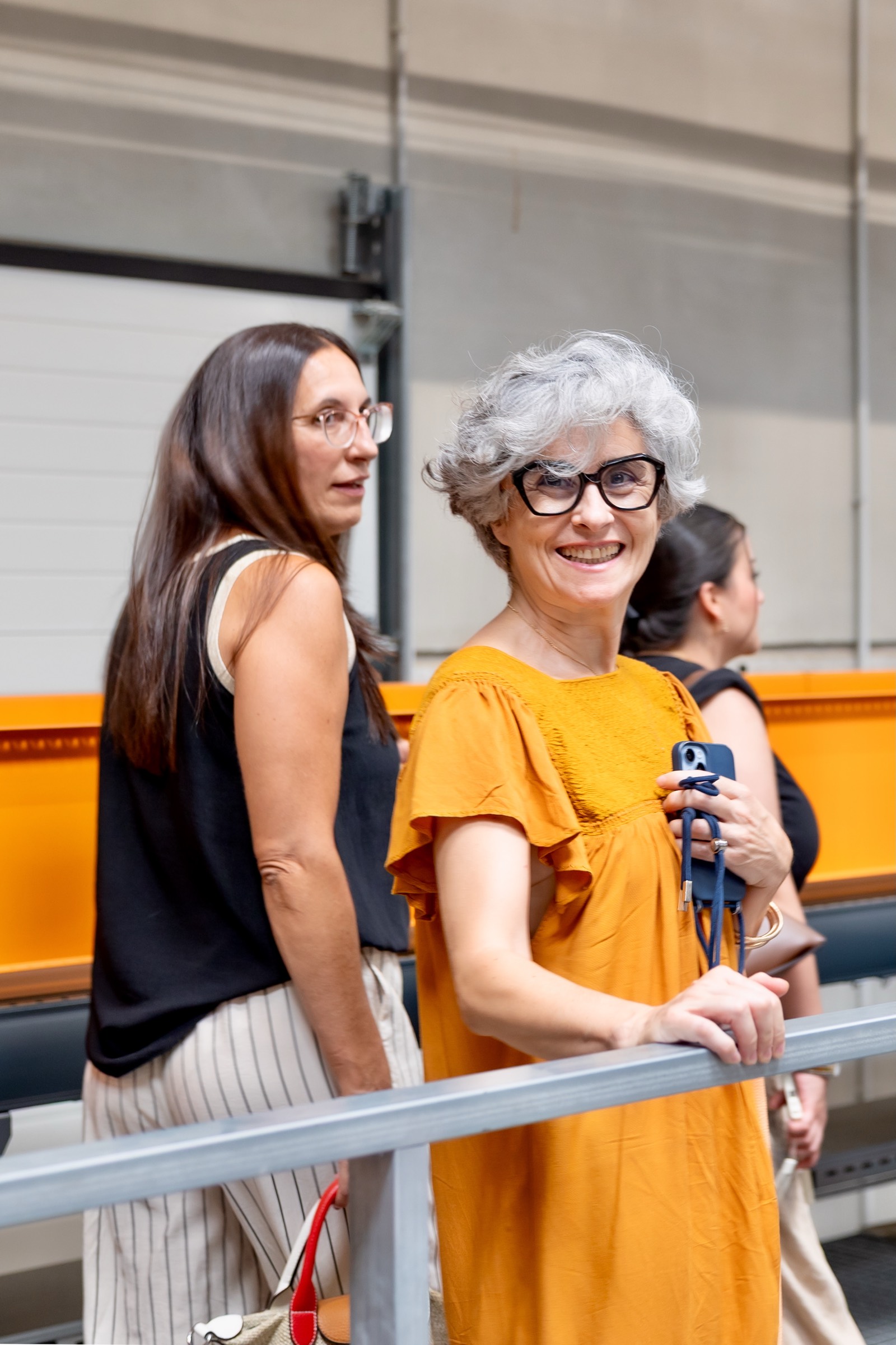 Dos mujeres de diferentes generaciones sonriendo, una con cabello oscuro y otra con cabello plateado, vestidas con ropa casual