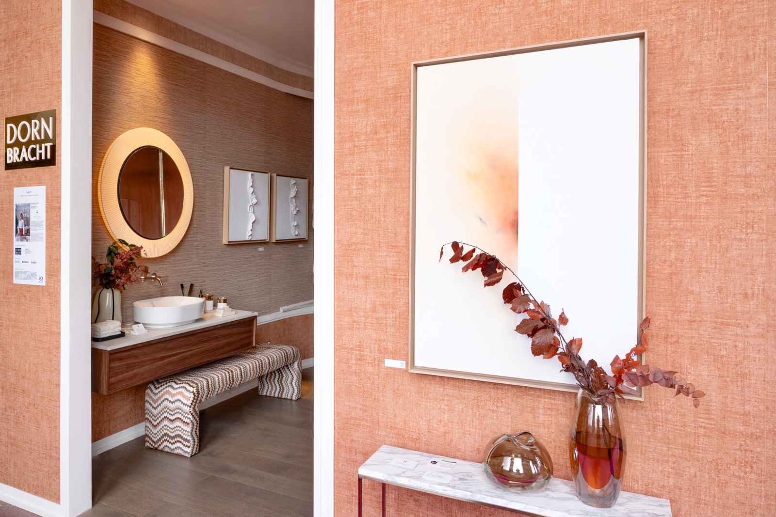 Diseño interior de cuarto de baño moderno con lavabo blanco, espejo redondo y decoración en tonos terracota y madera