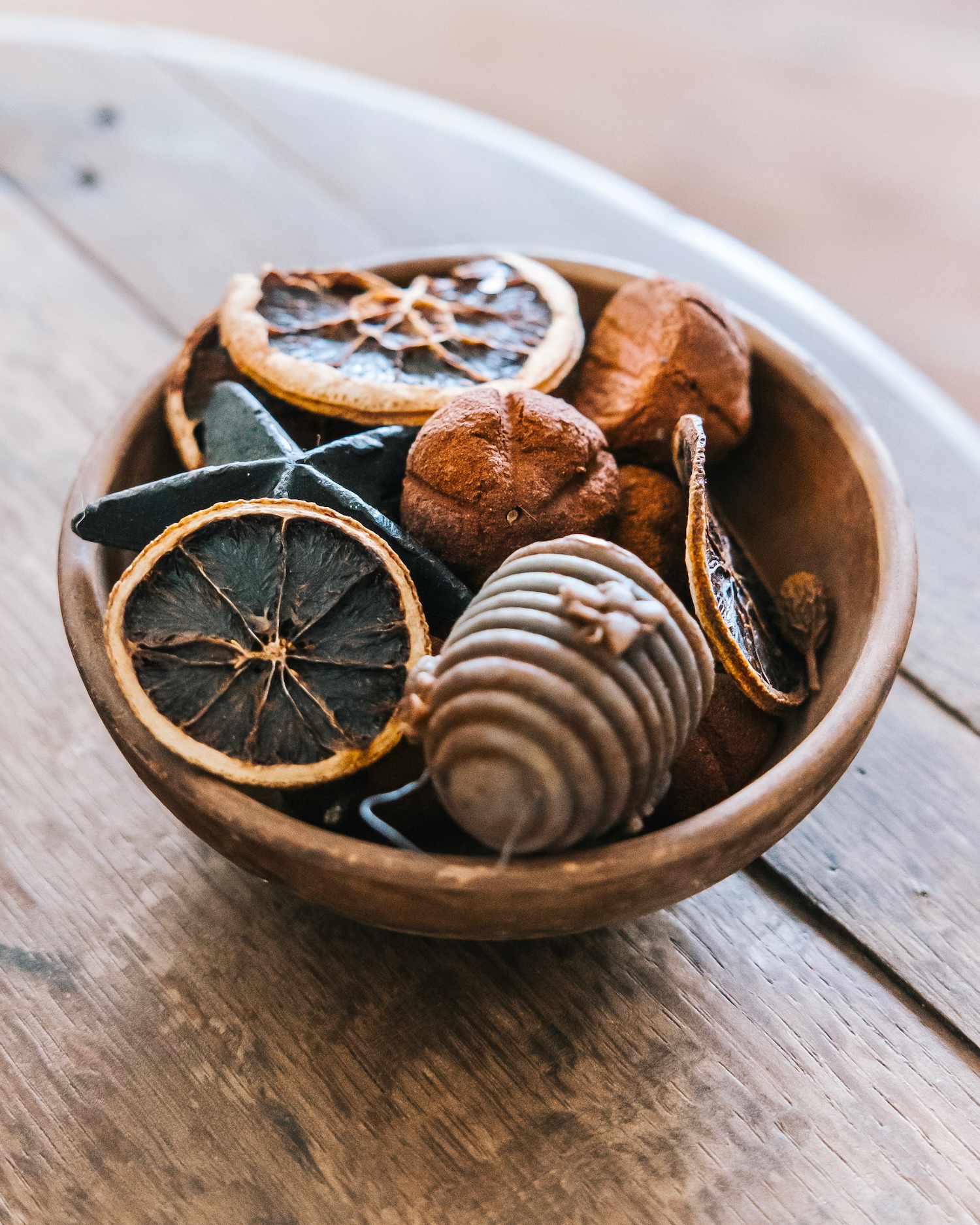 Cuenco de madera rústico conteniendo rodajas de naranja deshidratada y trufas de chocolate decoradas, sobre una superficie de madera. Composición artística de postres y cítricos secos.