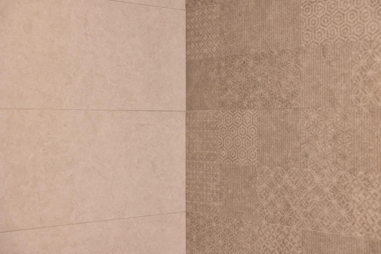 Imagen de una pared con dos tipos de azulejos: uno liso de color beige claro y otro con patrones geométricos en tonos marrones. Los azulejos decorativos muestran diferentes diseños repetitivos, creando un contraste visual interesante.