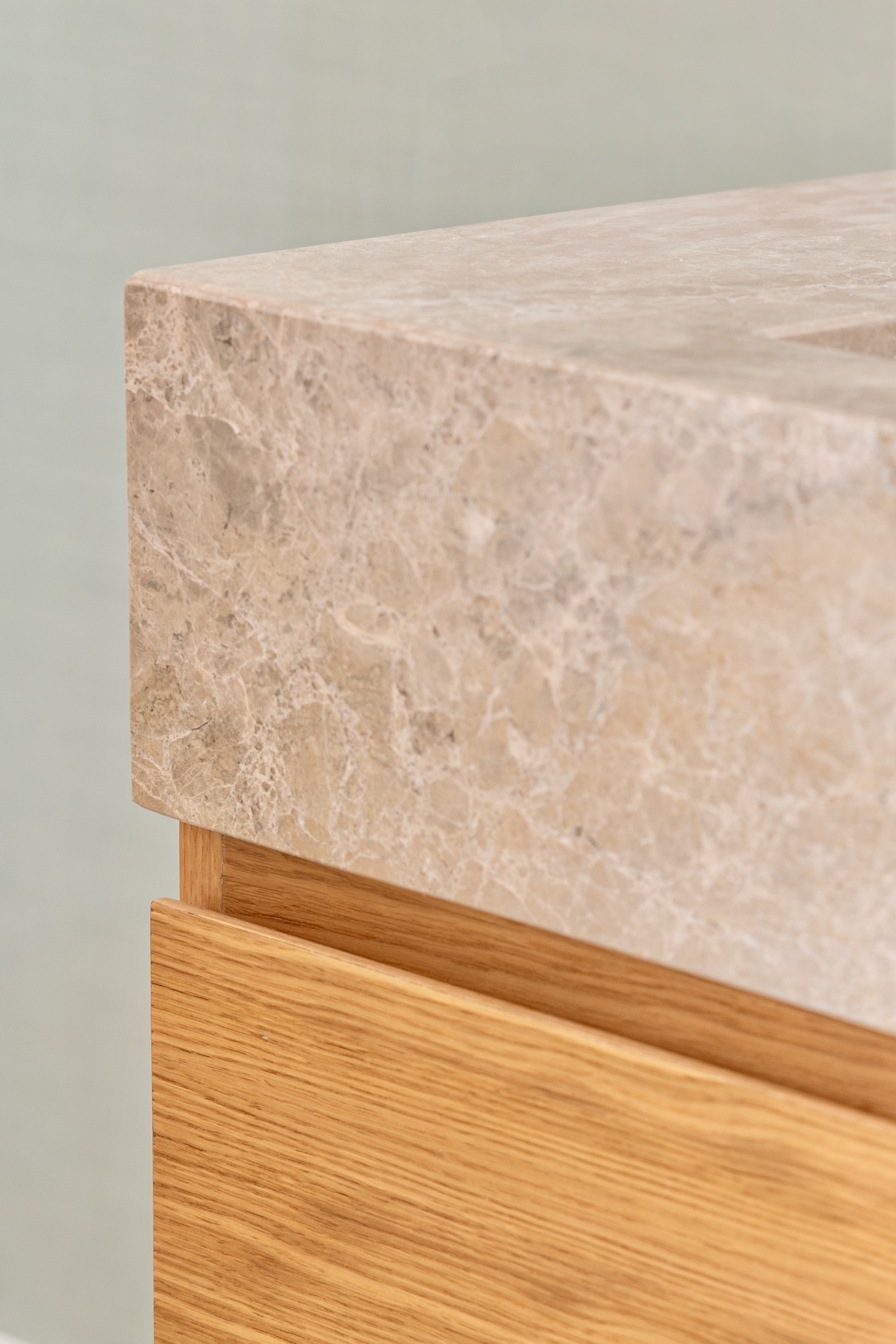 Primer plano de un objeto con superficie de mármol beige claro superpuesta sobre una base de madera de roble con textura natural